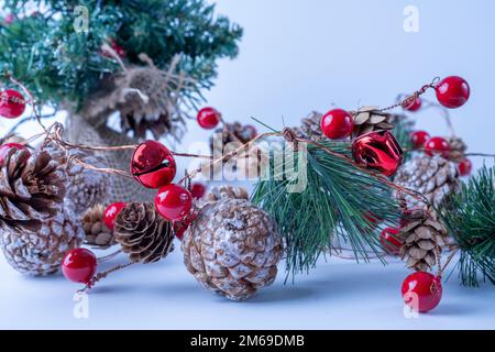 Saisonale weihnachten und Neujahr traditionelle Dekoration mit roten Beerenkugeln, Glocken und Kiefernzapfen mit künstlichem Schnee Stockfoto