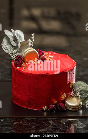 Ein bunter Kuchen steht auf einem schwarzen Tisch Stockfoto