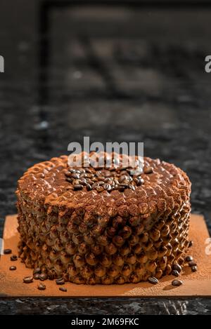 Ein bunter Kuchen steht auf einem schwarzen Tisch Stockfoto