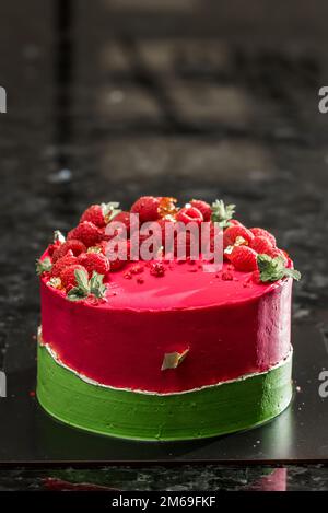 Ein bunter Kuchen steht auf einem schwarzen Tisch Stockfoto