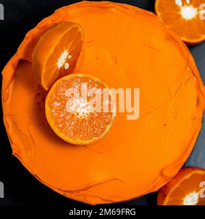 Ein bunter Kuchen steht auf einem schwarzen Tisch Stockfoto