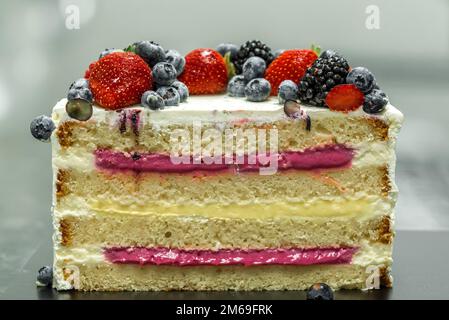 Ein bunter Kuchen steht auf einem schwarzen Tisch Stockfoto