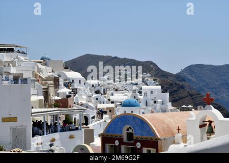 Oia, Santorin, Griechenland - 22. Juni 2022: Blick auf die Stadt Oia, die eingebundenen weißen Häuser sind auf den Klippen mit Blick auf die Caldera erbaut, Restaurant Stockfoto