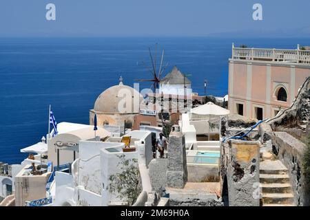 Oia, Santorin, Griechenland - 22. Juni 2022: Kapelle und alte Windmühle in Oia mit Blick auf das Ägäische Meer Stockfoto