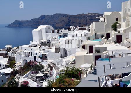 Oia, Santorin, Griechenland - 22. Juni 2022: Blick auf die Stadt Oia, die weißen Häuser sind auf den Klippen mit Blick auf die Caldera erbaut, einige Gebäude haben das Stockfoto