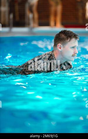 USA Navy Petty Officer 2. Class Sean Richardson, religiöser Programmspezialist, 26. Marine Expeditionary Unit, führt grundlegende Schwimmqualifikation in Camp Johnson, North Carolina, 21. April 2022 durch. Die grundlegende Schwimmqualifikation soll das Selbstvertrauen stärken, das erforderlich ist, um geistige und physische Widrigkeiten zu überwinden, die bei tatsächlichen Kampfwasserüberlebensszenarien auftreten können. Stockfoto