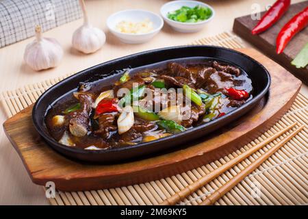 Foto von gebratenem Rindfleisch mit Sauce auf einer Kochplatte, dieses Gericht ist ein typisches asiatisches Gericht Stockfoto