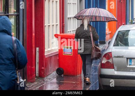 Clonakilty, West Cork, Irland. 3. Januar 2023. Nach Tagen relativ trockenen Wetters fiel heute sintflutartiger Regen auf West Cork und verursachte Flutkatastrophen. Bei starkem Regen in Clonakilty tragen die Leute Regenmäntel und verkuppeln sich unter Regenschirmen. Kredit: AG News/Alamy Live News Stockfoto