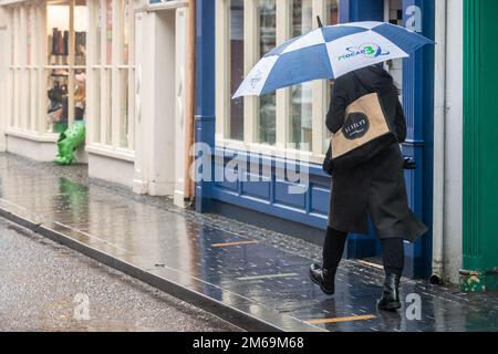 Clonakilty, West Cork, Irland. 3. Januar 2023. Nach Tagen relativ trockenen Wetters fiel heute sintflutartiger Regen auf West Cork und verursachte Flutkatastrophen. Bei starkem Regen in Clonakilty tragen die Leute Regenmäntel und verkuppeln sich unter Regenschirmen. Kredit: AG News/Alamy Live News Stockfoto