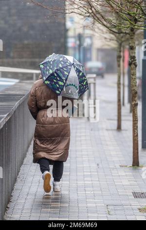 Clonakilty, West Cork, Irland. 3. Januar 2023. Nach Tagen relativ trockenen Wetters fiel heute sintflutartiger Regen auf West Cork und verursachte Flutkatastrophen. Bei starkem Regen in Clonakilty tragen die Leute Regenmäntel und verkuppeln sich unter Regenschirmen. Kredit: AG News/Alamy Live News Stockfoto