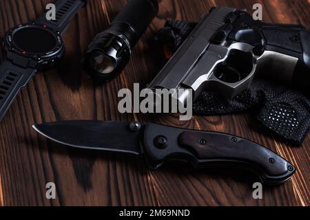 Klappbares Taschenmesser mit Pistole und Taschenlampe auf Holzhintergrund, Stockfoto