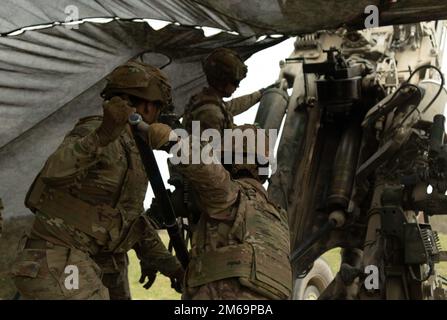 Mitglieder der Kanonencrew SPC. Amen-Ra Umoren und Pvt. Javan Haans mit Bulldog Battery, Artillerie-Geschwader, 2. Kavallerieregiment, laden einen M777A2 während des Trainings in Grafenwoehr, Deutschland, 21. April 2022. 7. der Grafenwoehr-Ausbildungsbereich des Army Training Command bietet höchste Qualitätsniveaus, Manövrierbereiche, Schulungshilfe und Unterstützung für US-amerikanische, gemeinsame und multinationale Kommandos, damit diese die Standards für die Ausbildung von Feuerwehrmännern sicher erreichen und aufrechterhalten und ihre Fähigkeiten verbessern können, um in jeder Betriebsumgebung erfolgreich zu sein. Stockfoto