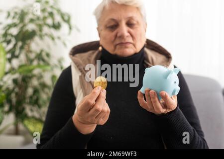 Geldverwaltungskonzept. Eine ältere Frau hält ein Sparschwein Stockfoto