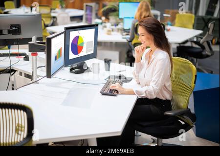 Geschäftsfrau mittleren Alters, die am Schreibtisch im Büro sitzt und den Computer nutzt. Professionelle Frau, die an Abschlüssen arbeitet. Stockfoto