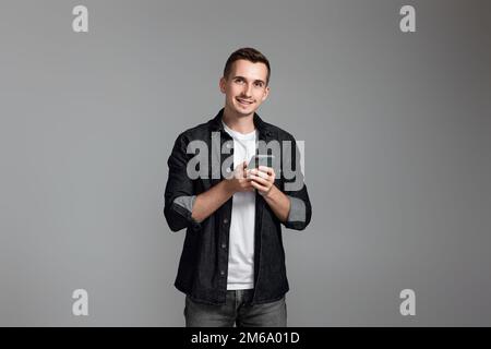 Mann mit Handy isoliert auf grauem Hintergrund. Stockfoto