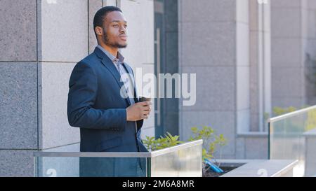 Afroamerikanischer Geschäftsmann pensive entspannte, nachdenkliche Unternehmer Büroangestellter Manager männlicher Arbeitgeber, der auf dem Balkon steht und nachdenkt Stockfoto