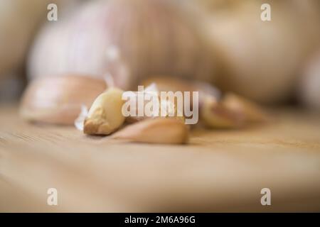 Knoblauch, Allium sativum, Knoblauchzehen auf einem Schneidebrett in der Küche Stockfoto