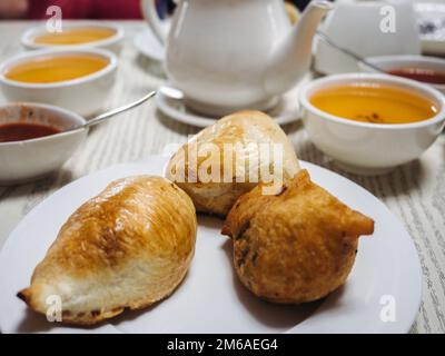 Frisches, heißes Brötchen und eine Tasse duftender Tee. Sonniger, klarer Tag. Nahaufnahme, draußen, keine Menschen. Konzept für leckere und gesunde Speisen Stockfoto