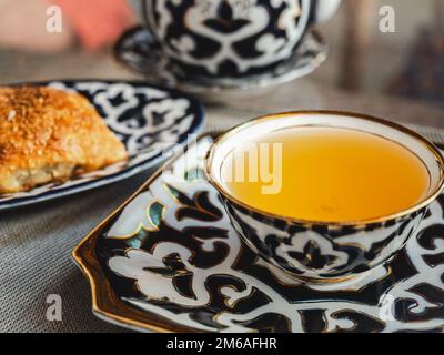 Frisches, heißes Brötchen und eine Tasse duftender Tee. Sonniger, klarer Tag. Nahaufnahme, draußen, keine Menschen. Konzept für leckere und gesunde Speisen Stockfoto