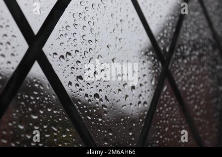 An einem besonders nassen Tag in den Vororten von Belfast, Nordirland, fällt Regen auf ein bleihaltiges Fenster. 14. Februar 2021 11:57 Uhr. Stockfoto