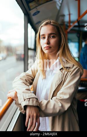 Porträt einer Frau in einem Mantel und einem weißen Hemd, die im Bus steht Stockfoto