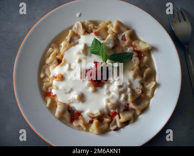 Berühmte türkische Essensmanti auf dem Tisch. Nahaufnahme handgemachter Mantis. Bereit für traditionelle türkische mantı. Türkische hausgemachte Knödel, Stockfoto