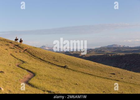 Zwei Fahrer fahren bei Sonnenaufgang auf einem Hügelpfad entlang. Stockfoto