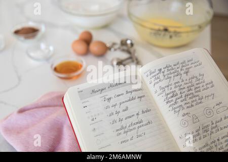 Merigue-Rezept im Rezeptbuch mit Backzutaten Stockfoto