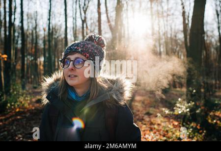Frau mit Hut und Brille draußen in der eiskalten Luft bei Sonnenaufgang Stockfoto