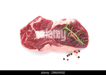 Rohes Steak, isoliert auf Weiß. In Scheiben gegrilltes Fleischsteak New York oder Ribeye mit Gewürzen, Rosmarin und Pfeffer auf weißem Hintergrund. Draufsicht. Modell. Stockfoto