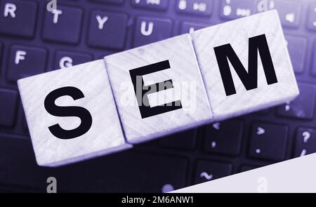 SEM Search Engine Marketing auf einem hölzernen Würfel geschrieben, der auf Computertastatur gesetzt wird. Optimierung Online Business Technologie Konzept Stockfoto