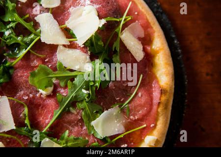 Pizza-Rindfleisch-Carpaccio. Neapolitanische Pizza mit Tomatensauce, Käse und Rindfleisch. Italienisches Rezept. Stockfoto