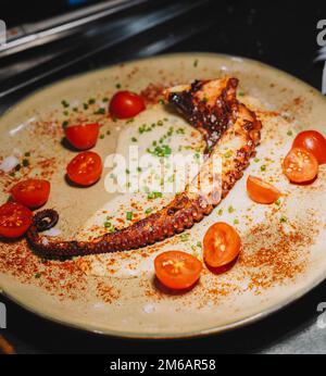 Gourmetgericht mit gegrilltem Kraken-Tentakel in einem schicken Restaurant Stockfoto