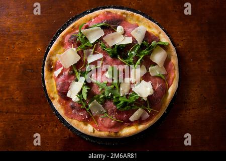 Pizza-Rindfleisch-Carpaccio. Neapolitanische Pizza mit Tomatensauce, Käse und Rindfleisch. Italienisches Rezept. Stockfoto