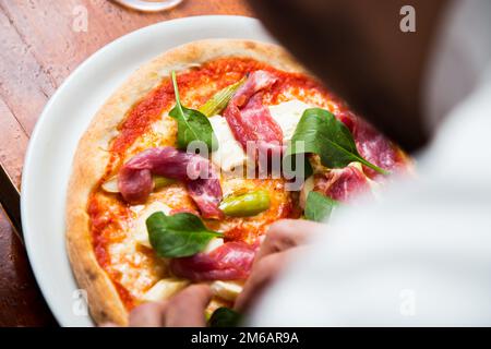 Pizza-Rindfleisch-Carpaccio. Neapolitanische Pizza mit Tomatensauce, Käse und Rindfleisch. Italienisches Rezept. Stockfoto