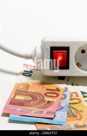 Umschaltbare Steckdosenleiste, Euro-Banknoten, symbolische Kosten für Bildenergie, Stromkosten, Energieeinsparung Stockfoto