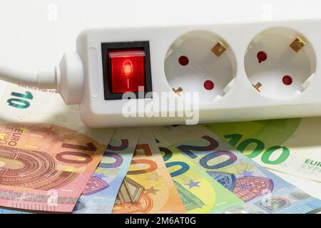 Umschaltbare Steckdosenleiste, Euro-Banknoten, symbolische Kosten für Bildenergie, Stromkosten, Energieeinsparung Stockfoto