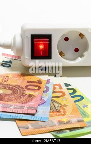 Umschaltbare Steckdosenleiste, Euro-Banknoten, symbolische Kosten für Bildenergie, Stromkosten, Energieeinsparung Stockfoto