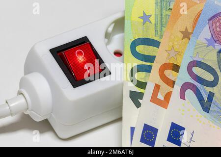 Umschaltbare Steckdosenleiste, Euro-Banknoten, symbolische Kosten für Bildenergie, Stromkosten, Energieeinsparung Stockfoto