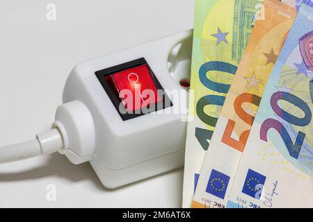 Umschaltbare Steckdosenleiste, Euro-Banknoten, symbolische Kosten für Bildenergie, Stromkosten, Energieeinsparung Stockfoto