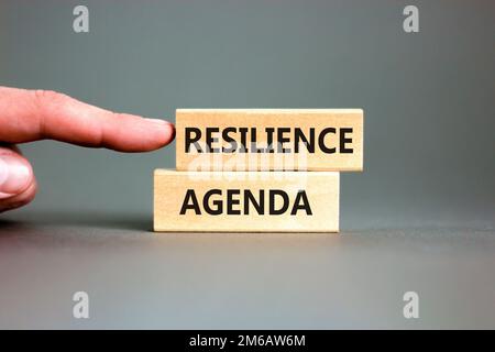 Symbol für Resilienz-Agenda. Konzeptwort „Resilience Agenda“ auf Holzblöcken getippt. Wunderschöner grauer Tischhintergrund. Geschäftsmannshand. Business und Stockfoto