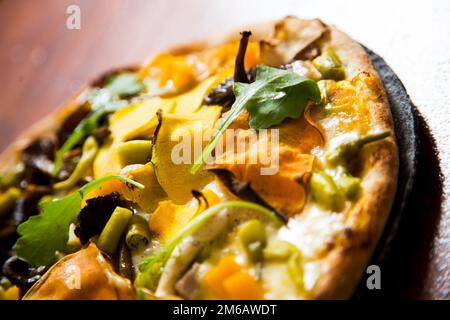 Pizza mit Rucola, Kürbis, Pilzen und Mozzarella. Stockfoto