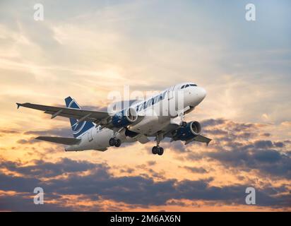 Bukarest, Rumänien - August 2022: TAROM Airbus A318 Flugzeug fliegt gegen den Himmel bei Sonnenuntergang. Das Flugzeug startet vom internationalen Flughafen Henri Coanda Stockfoto