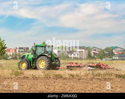 Ein Traktor auf dem landwirtschaftlichen Feld pflügt das Land und bereitet das Erntegut vor. Stockfoto