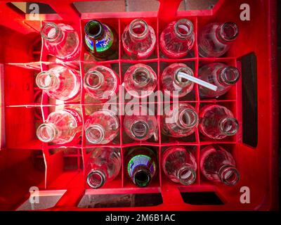 Rote Box mit verschiedenen leeren Coca-Cola-Flaschen. Stockfoto