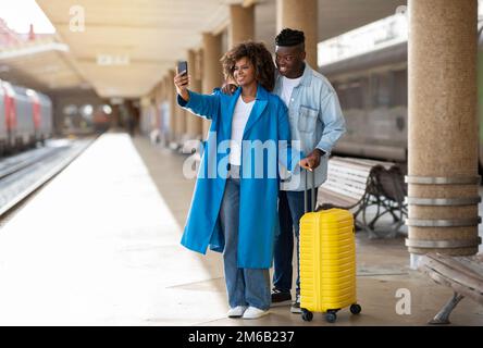 Lächelndes Schwarzes Paar Am Bahnhof, Das Selfie Mit Smartphone Nimmt Stockfoto