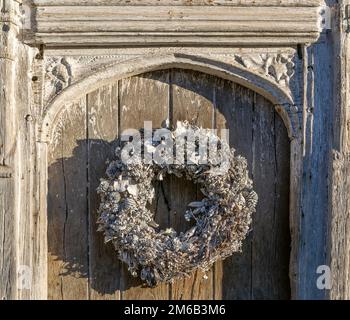 Silberner weißer Weihnachtskranz an der alten Tür in Lavenham, Suffolk, England, Großbritannien Stockfoto