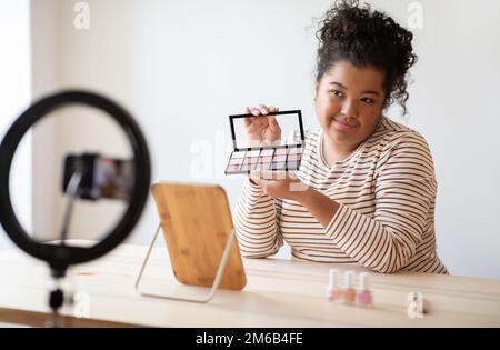 Hübsche, attraktive junge Frau, Schönheitsbloggerin, die Lidschatten zeigt Stockfoto