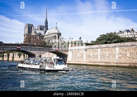 Ein Touristenboot auf der seine fährt an Notre Dame unter der Brücke Pont Archeveche in Paris vorbei. Stockfoto