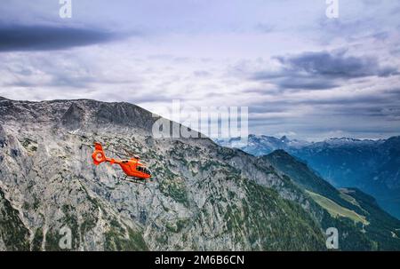 Ein medizinischer Helikopter transportiert Verletzte aus großer Höhe in den deutschen Alpen. Stockfoto